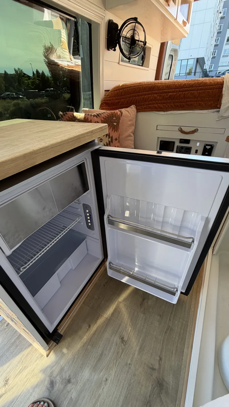 Open refrigerator beneath Pebbles’ kitchen counter beside the seating area