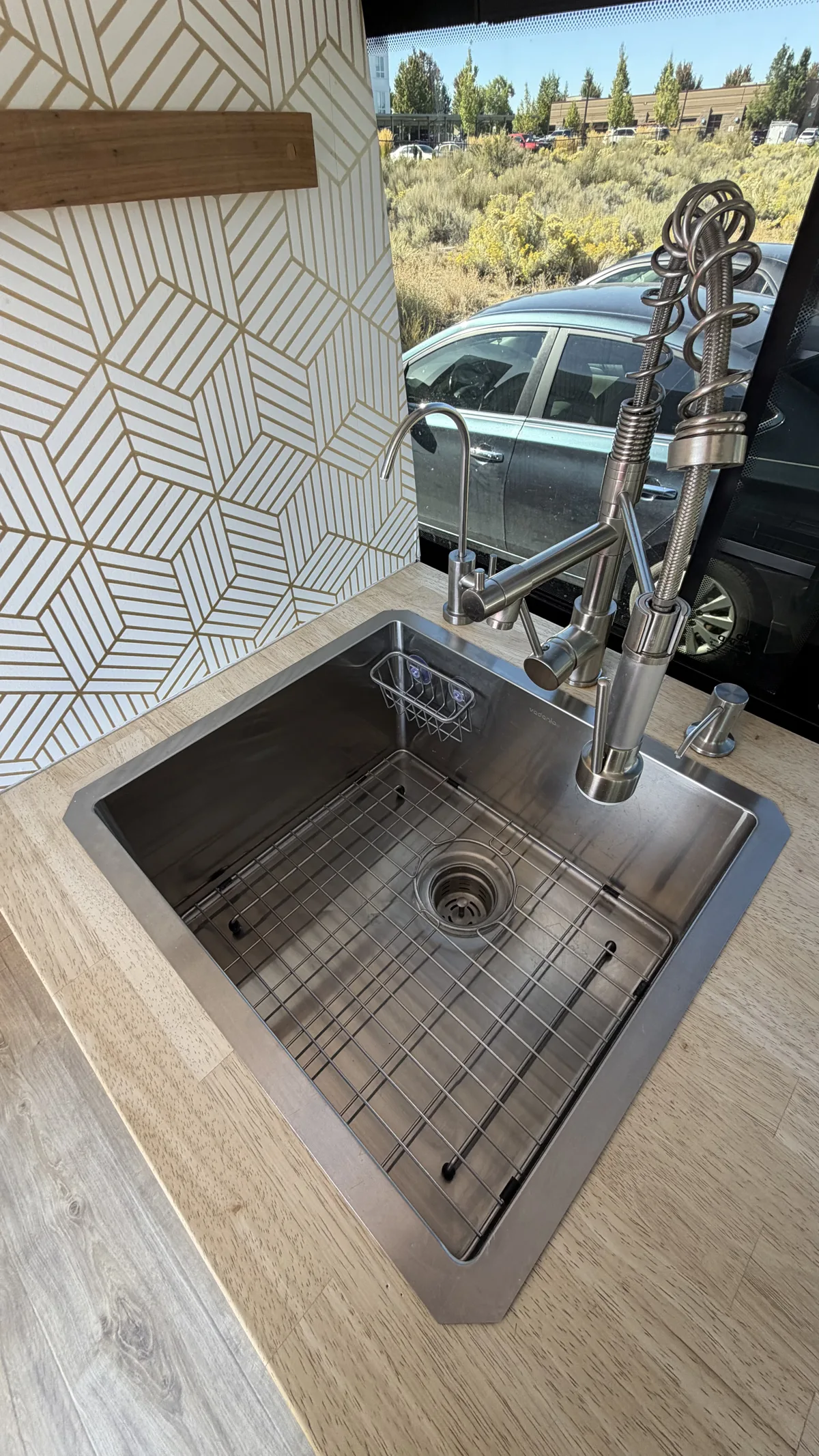 Pebbles’ stainless steel kitchen sink, wood countertop, and patterned backsplash